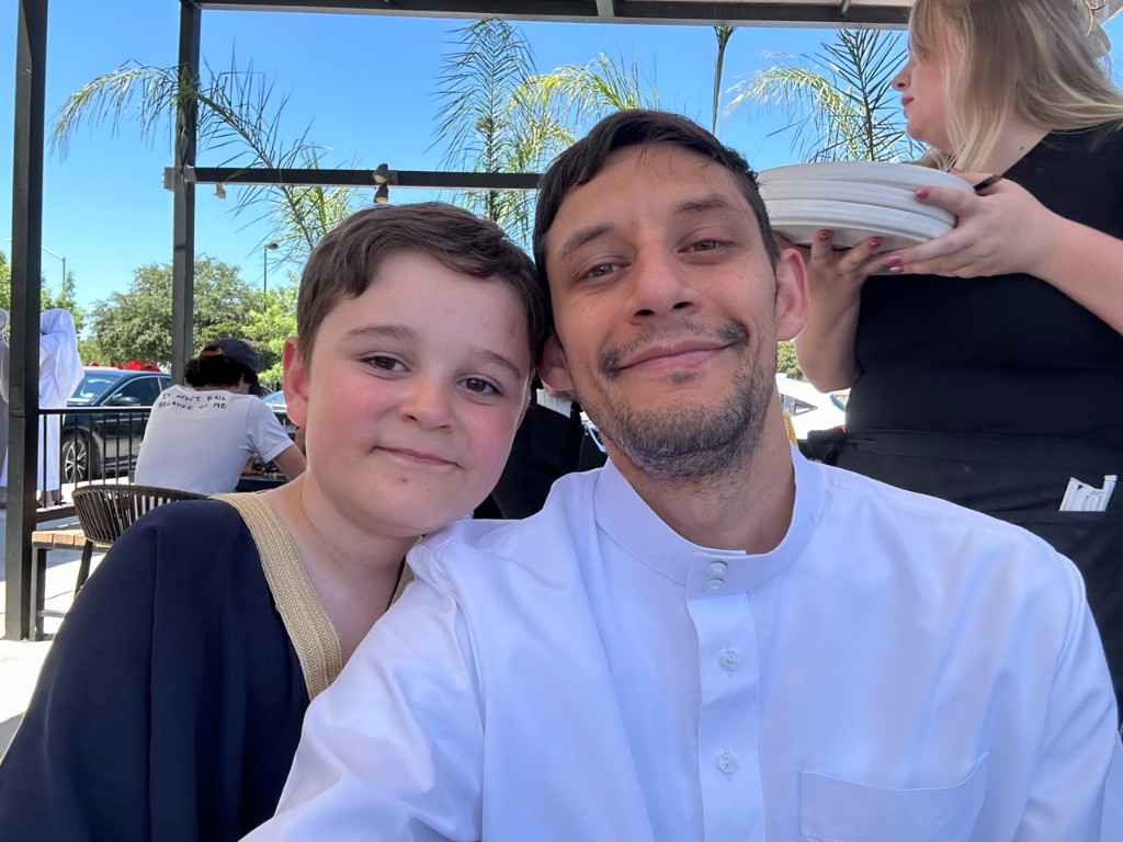Aziz with his father outdoors at a patio restaurant