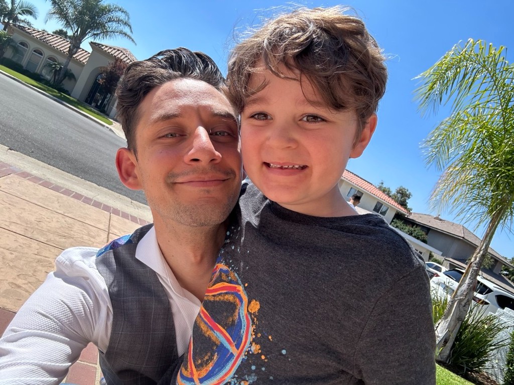 Aziz with his father taking a selfie on a sunny street