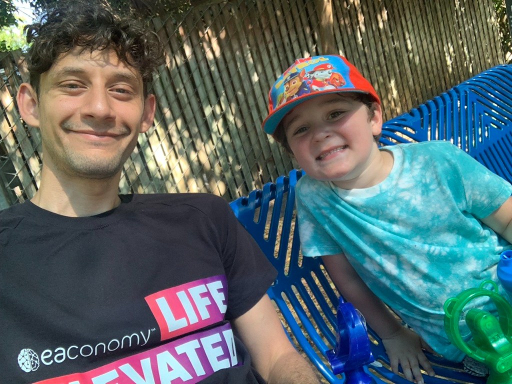 Aziz with his father smiling on a blue bench in a yard